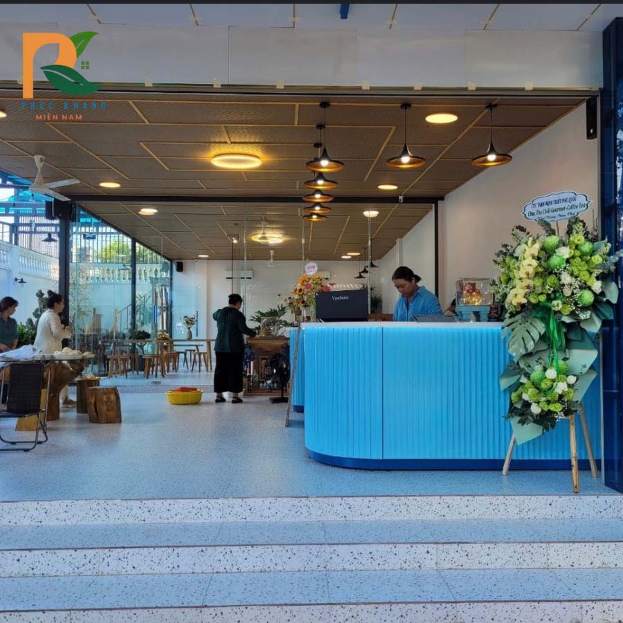 4 điểm khiến cót ép nhân tạo trở thành lựa chọn lý tưởng của The Chill Gourmet 4 Sảnh đón khách của quán cafe với quầy lễ tân xanh và trần cót ép nhân tạo vàng nhạt.