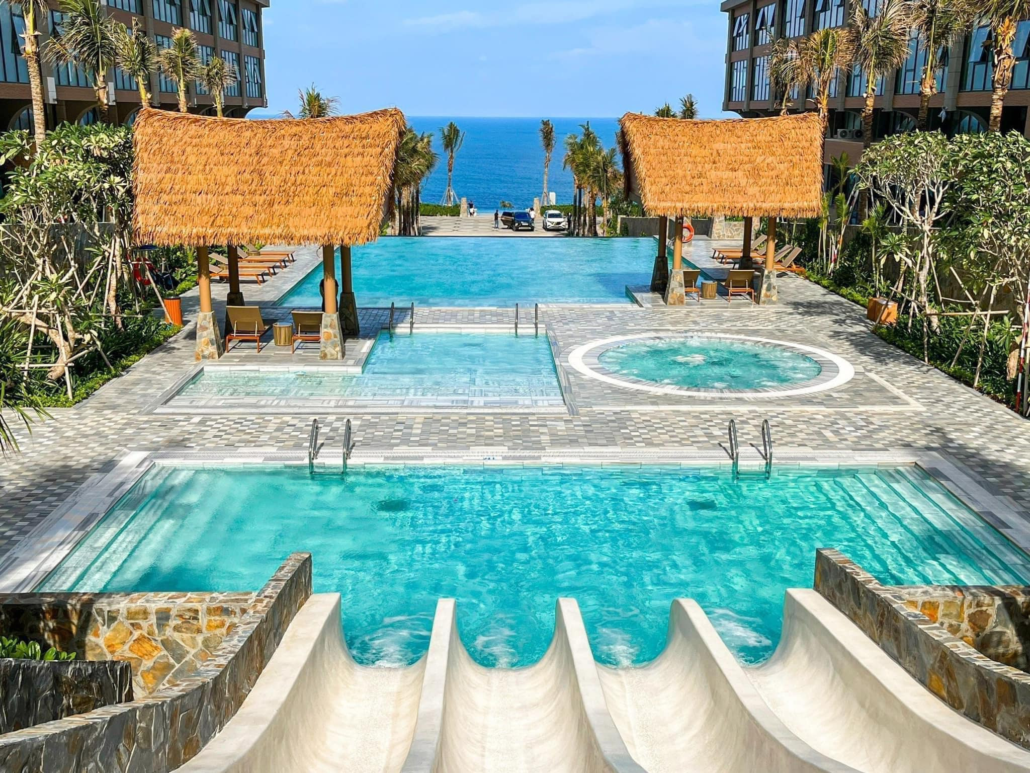 Chòi Rơm Nhân Tạo – Xu Hướng Thiết Kế Độc Đáo Năm 2025 1 Hồ bơi resort với mái chòi lợp mái lá nhân tạo, hướng nhìn ra biển xanh